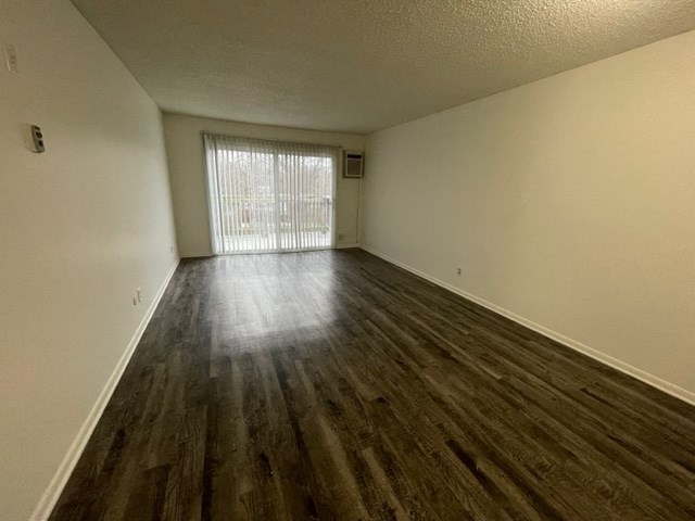 an empty living room with wood flooring and a window