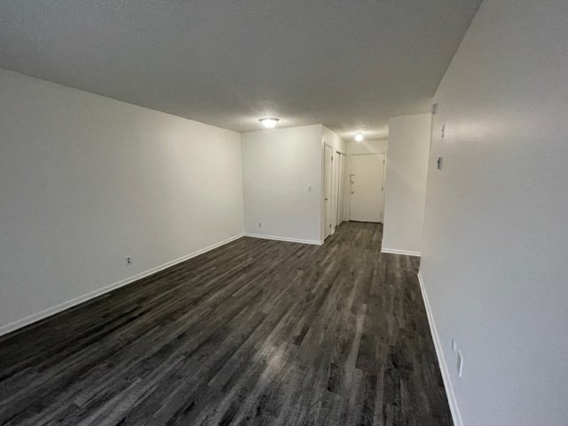 an empty living room with wood flooring and white walls