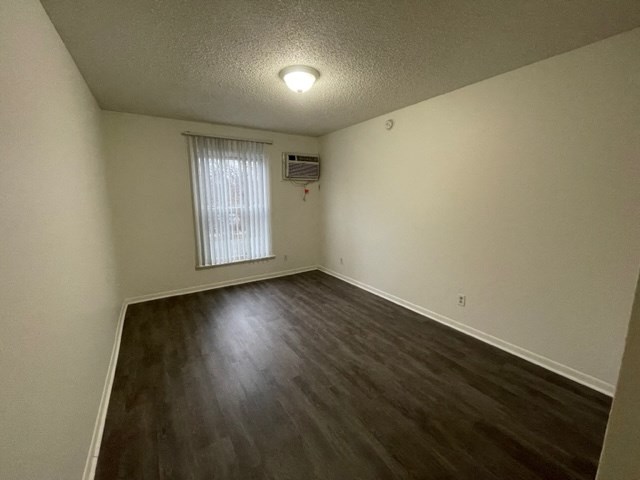 an empty living room with wood flooring and a window