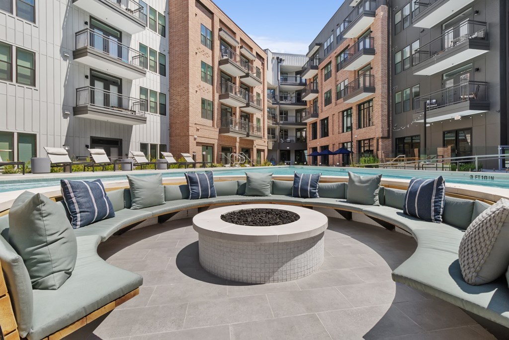 A modern outdoor seating area with a fire pit in the center.