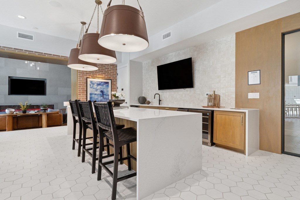 A modern kitchen with a white marble island and dark wood chairs.