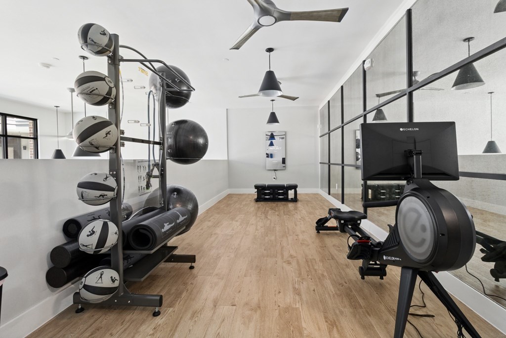 A gym with a wooden floor and a variety of exercise equipment.