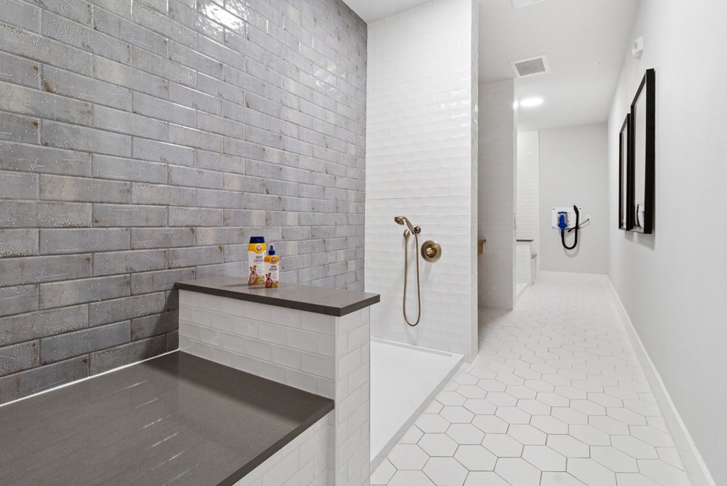 A bathroom with a white tiled floor and a grey tiled shower area.