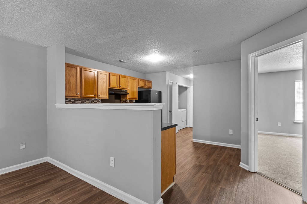 the living room and kitchen of an empty house with wood flooring