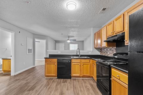 an empty kitchen with wood flooring and black appliances