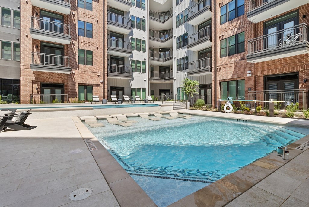 A swimming pool in front of a multi-story apartment building.