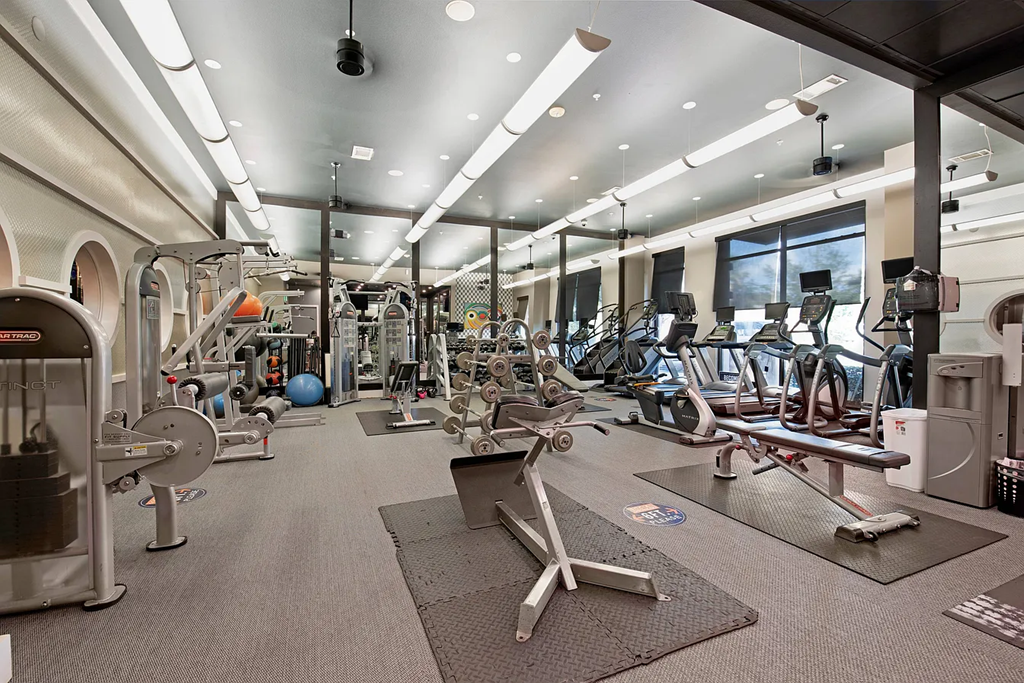 A gym with a variety of equipment including weights and cardio machines.