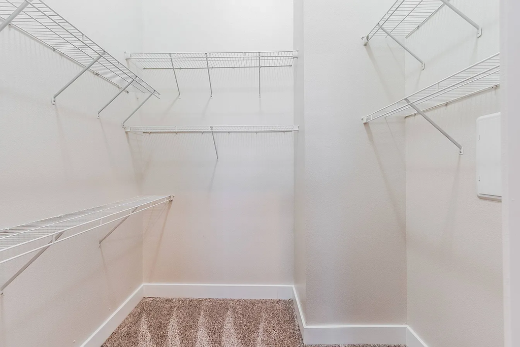 Empty white walk in closet with shelves.