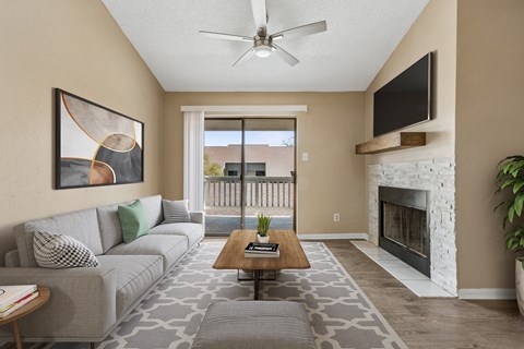 A living room with a grey couch, a coffee table, a fireplace, and a painting on the wall.