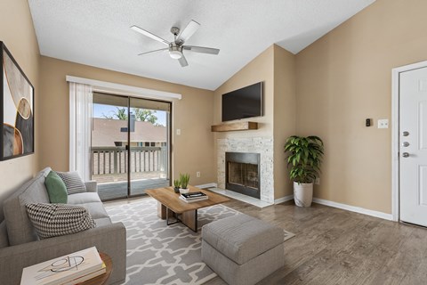 A living room with a grey couch, a coffee table, a fireplace, and a flat screen TV mounted above the fireplace.