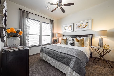 A bedroom with a large bed, a ceiling fan, and a side table with a lamp.