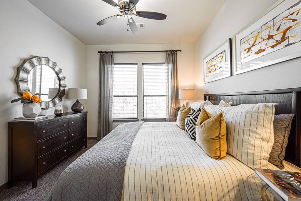 A bedroom with a large bed, a dresser, and a ceiling fan.