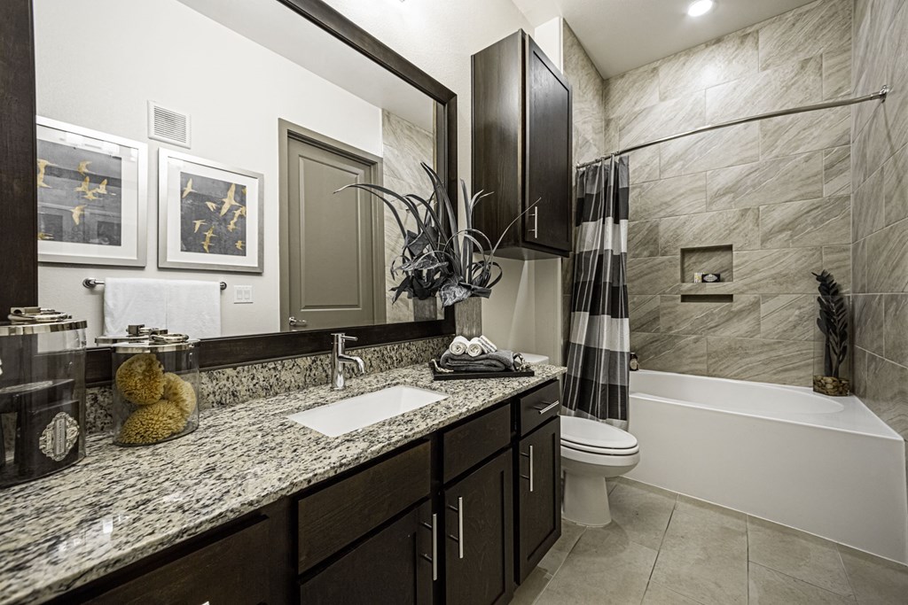 A bathroom with a marble countertop and a white bathtub.