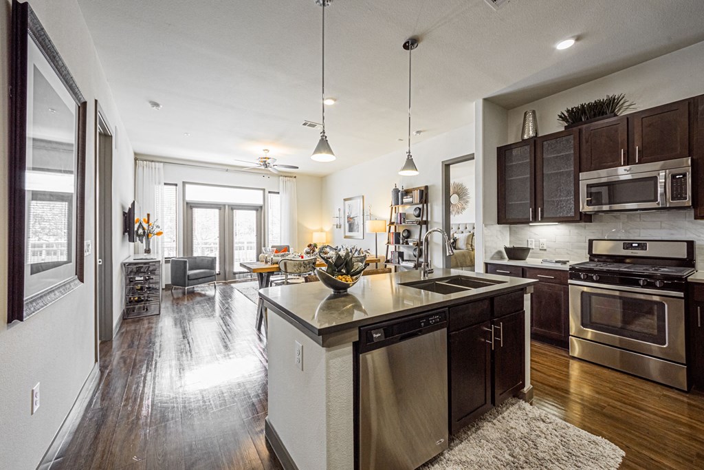 A modern kitchen with dark wood floors and stainless steel appliances.