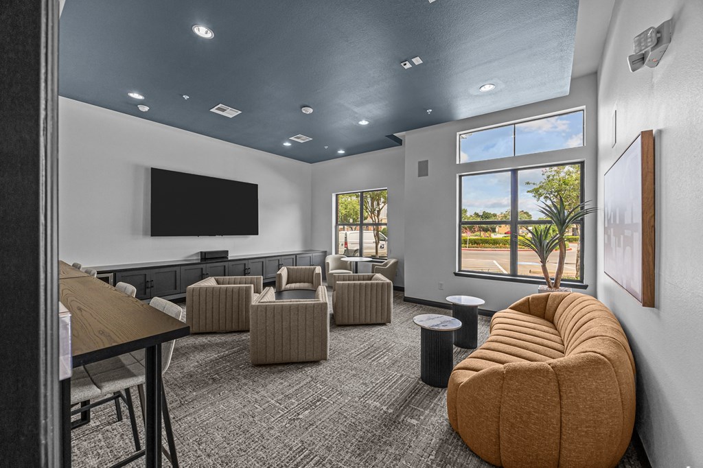 A room with a large window, a flat screen TV, and a comfortable seating area.