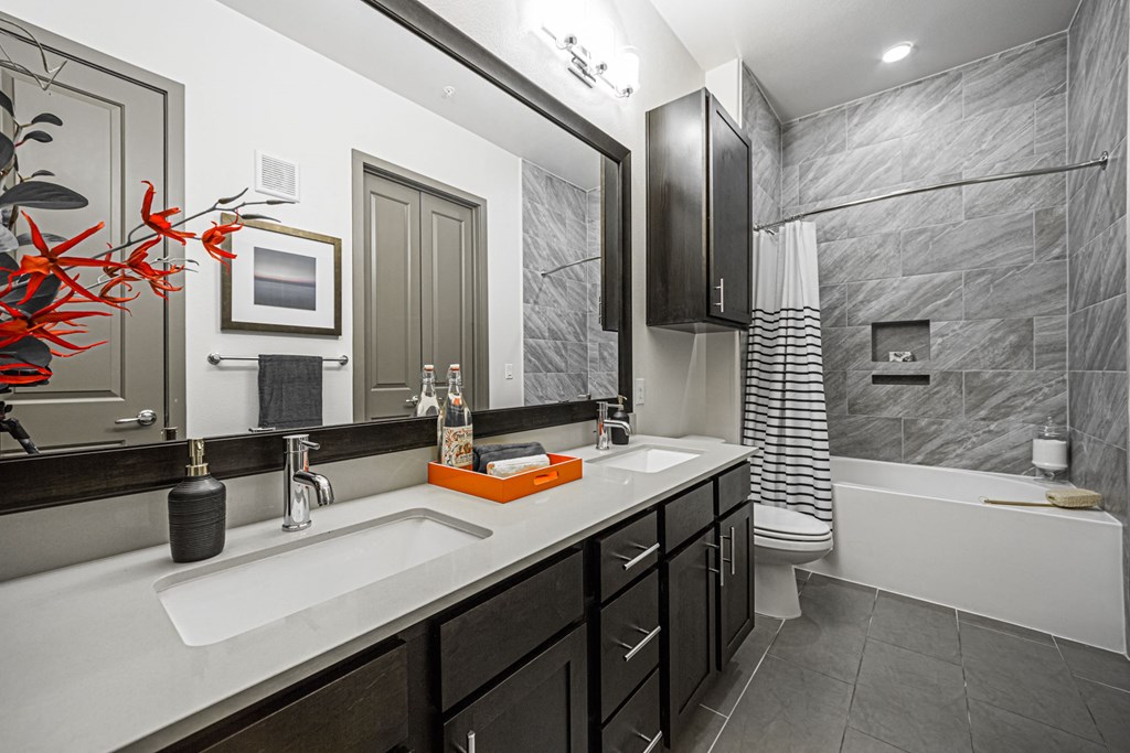 A bathroom with a sink, mirror, and bathtub.