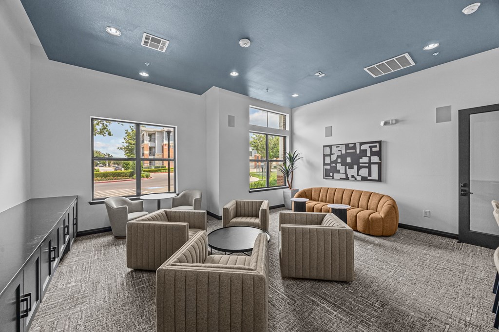 A spacious room with grey carpet and a variety of seating options.