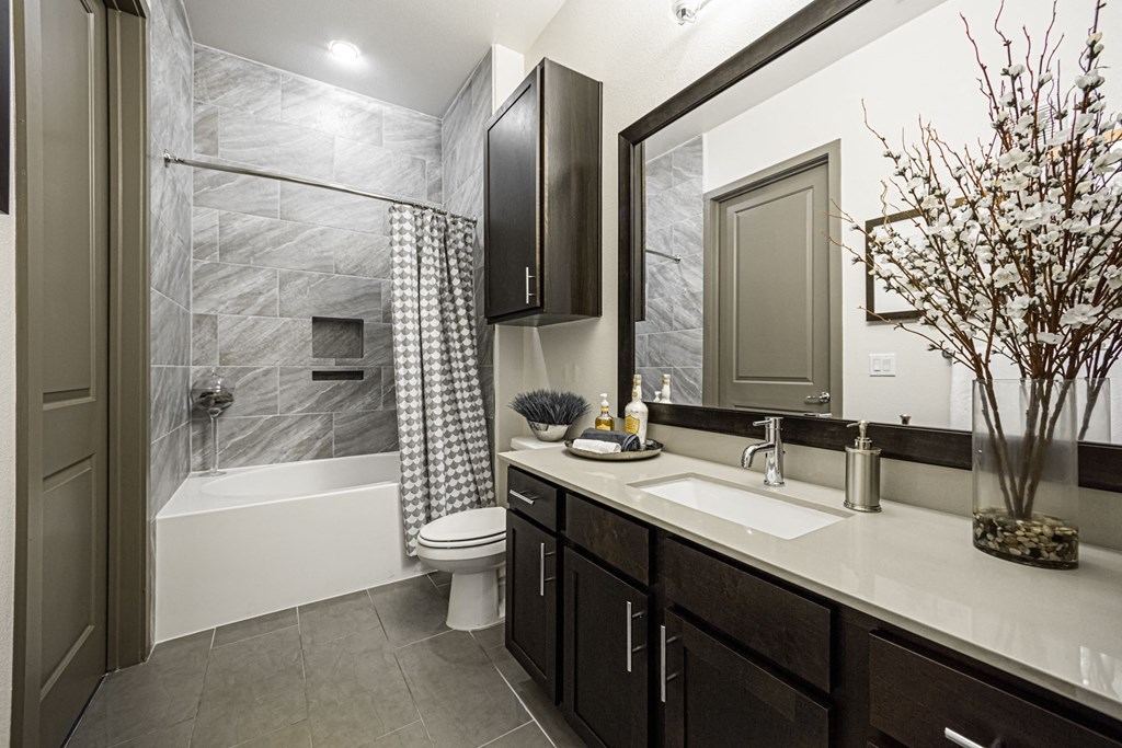 A bathroom with a black cabinet and a white sink.