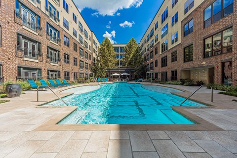 A long rectangular pool in the middle of a courtyard surrounded by buildings.