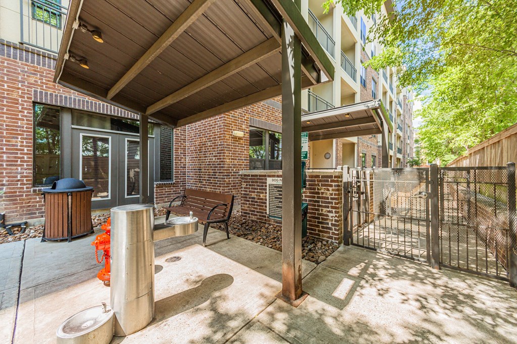 a patio with a bench and a fence next to a brick building