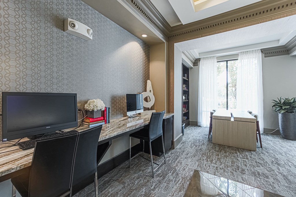 A room with a desk, chairs, and a computer monitor.