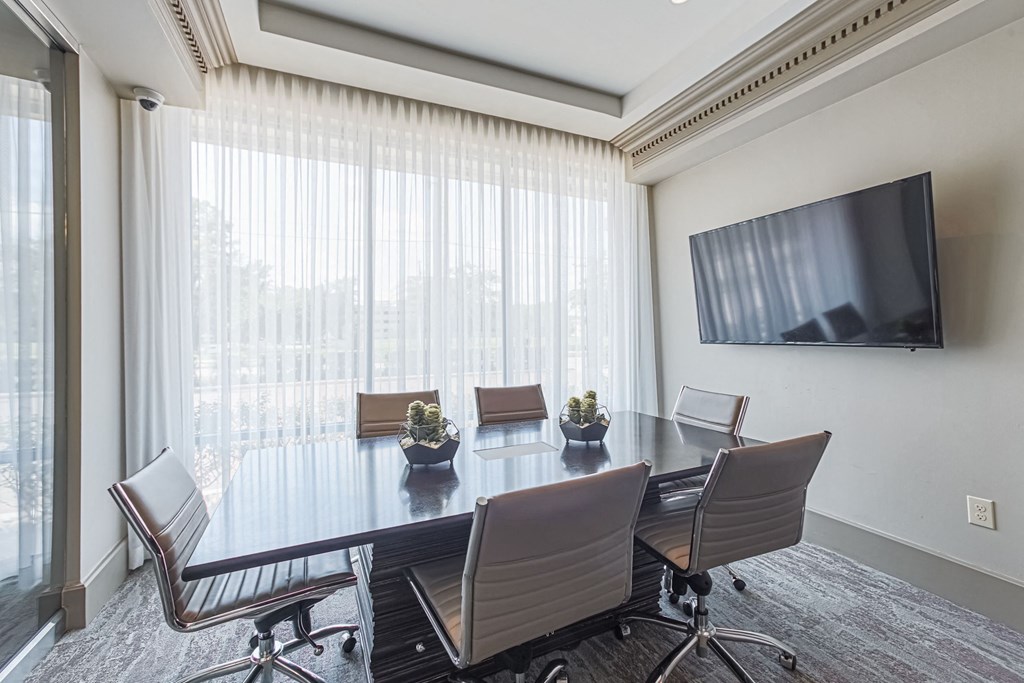 a conference room with a table and chairs and a television