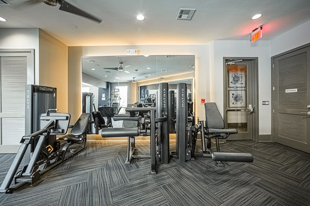 A gym with a variety of equipment including a treadmill, weights, and a bench.