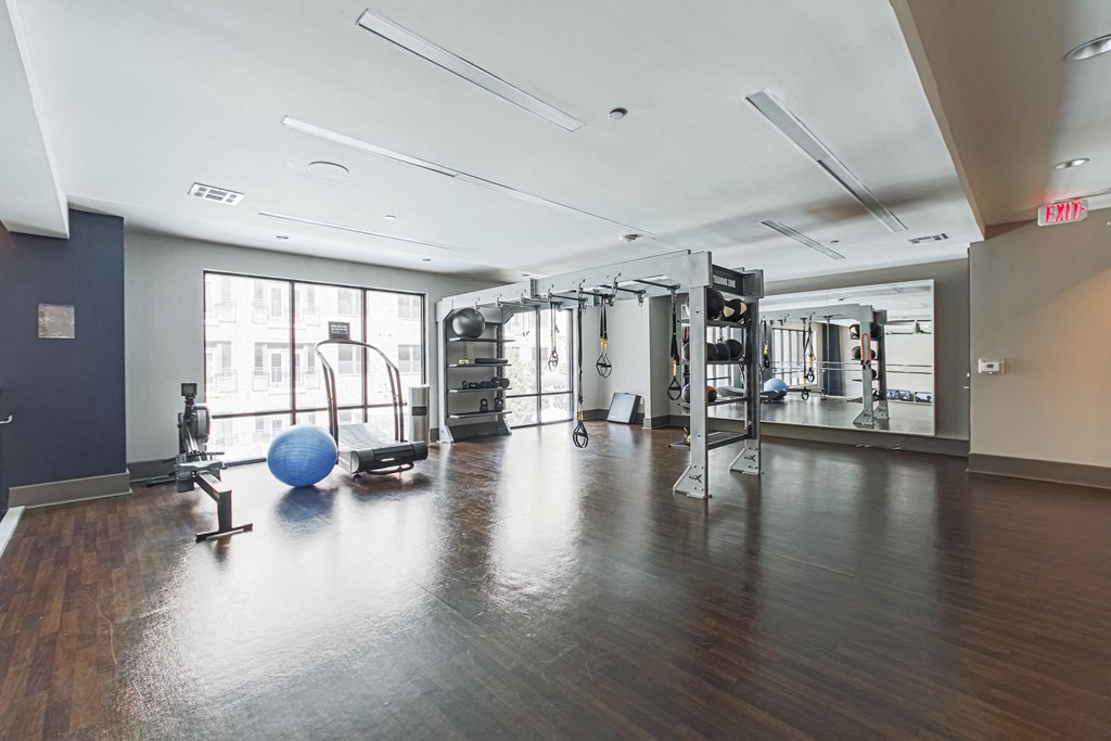 A gym with a blue ball and a mirror on the wall.