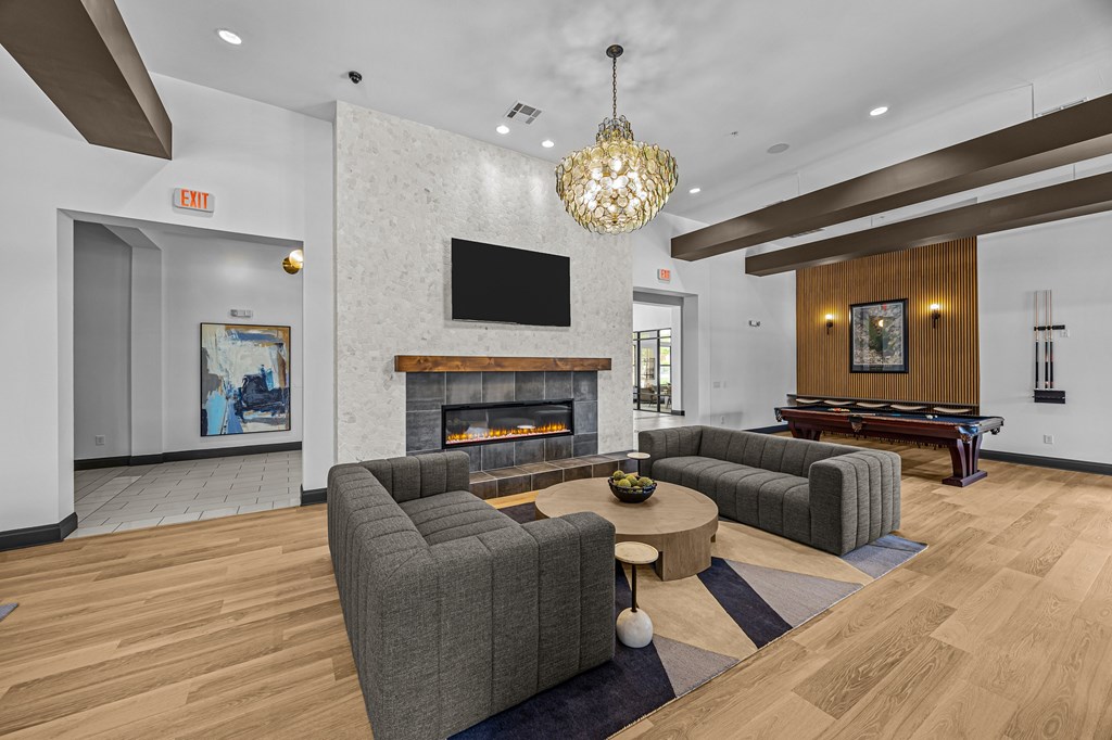 A living room with a grey couch and a fireplace.
