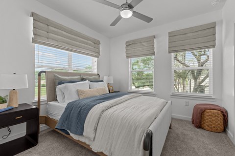 A bedroom with a large bed and a ceiling fan.