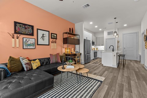 A living room with a black leather couch and a striped rug.