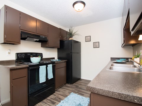 A kitchen with brown cabinets and black appliances.