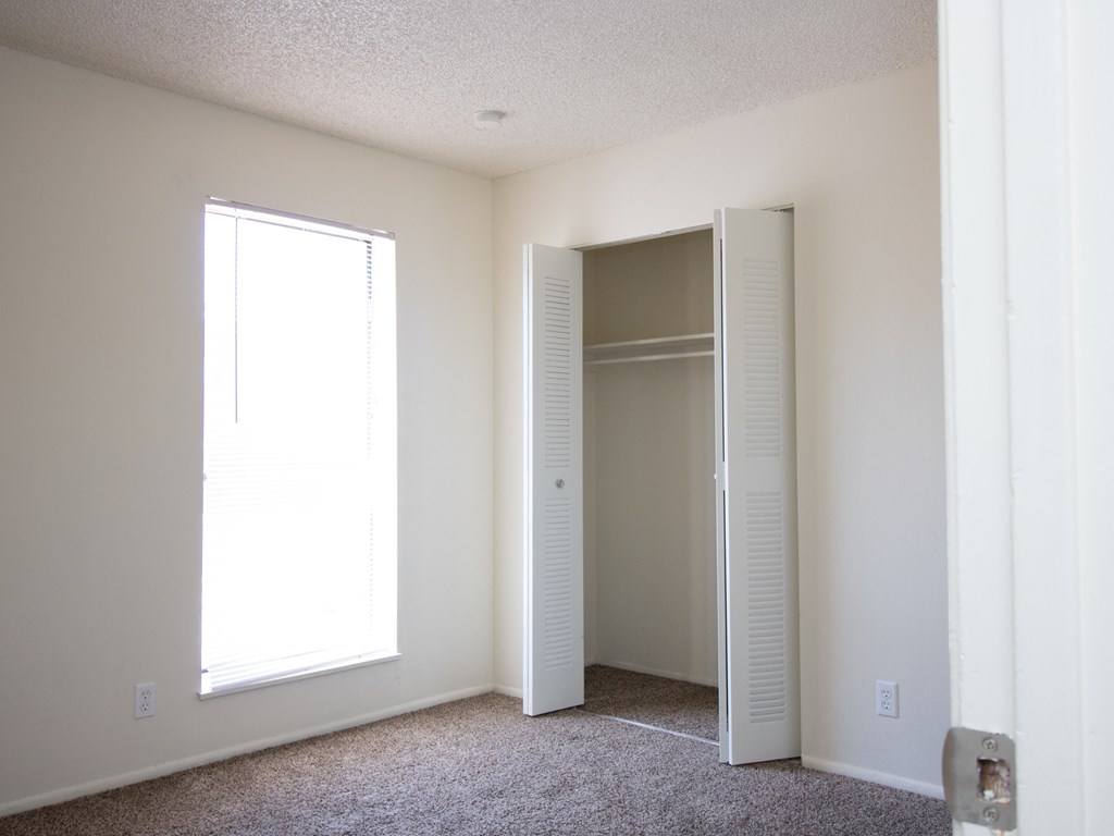a bedroom with a large window and a closet