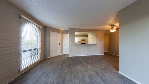 an empty living room with a large window and wood flooring