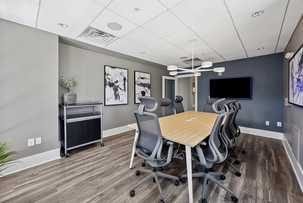 A conference room with a wooden table and grey chairs.