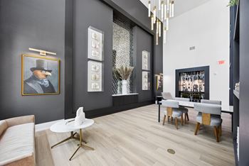 A modern living room with a grey couch, a white coffee table, and a painting of a man in a hat.