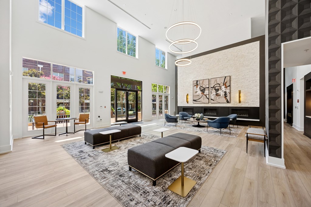 A modern living room with a black and white rug and a large black couch.