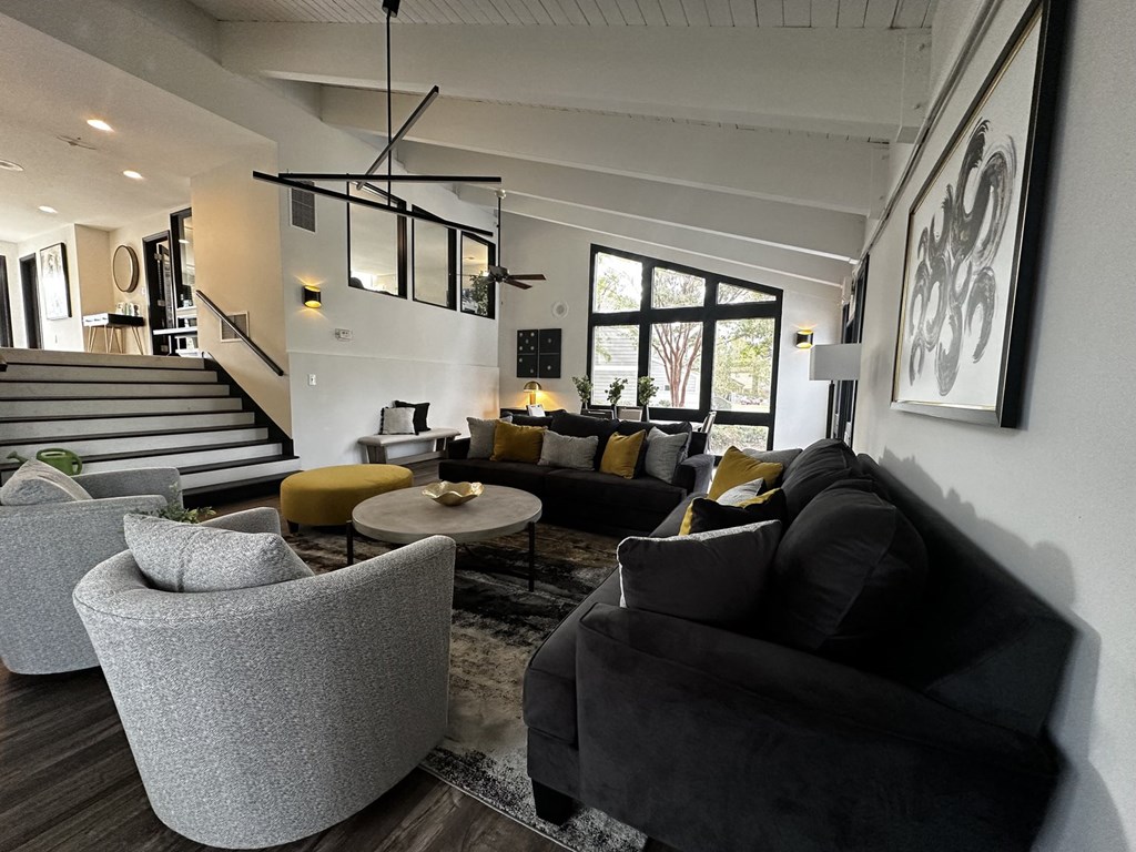 a living room with couches and chairs and a staircase