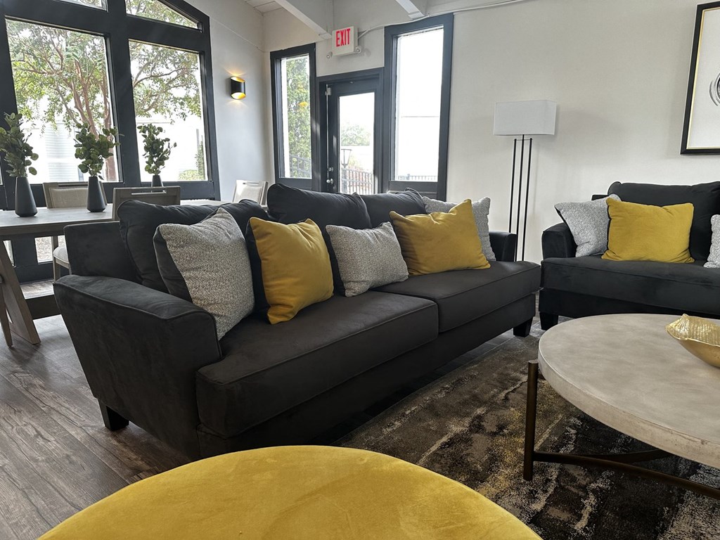 a living room with a black couch and yellow pillows
