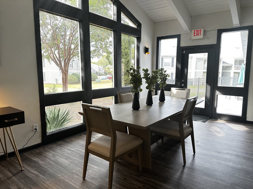 a dining room with a table and chairs and large windows