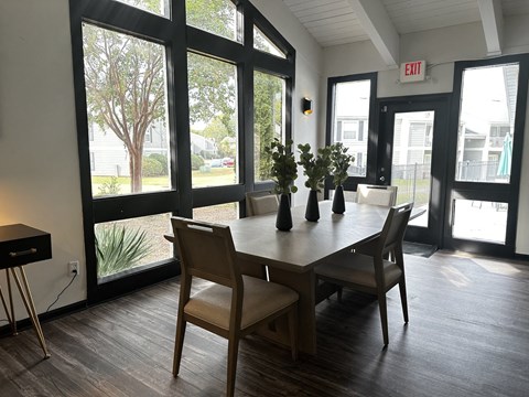 a dining room with a table and chairs and large windows