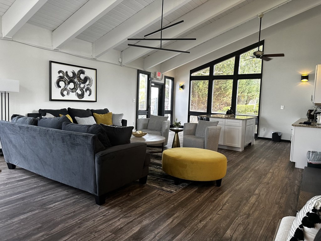 a living room with a gray couch and a yellow ottoman