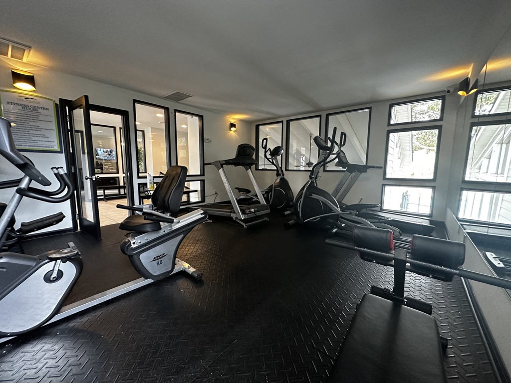 a gym with cardio equipment and windows in a building