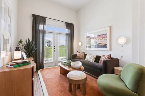 A living room with a green chair and a black couch.