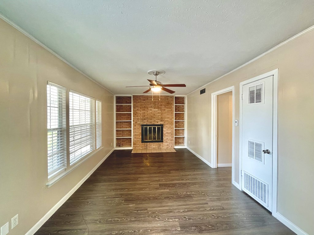 an empty living room with a fireplace and a ceiling fan