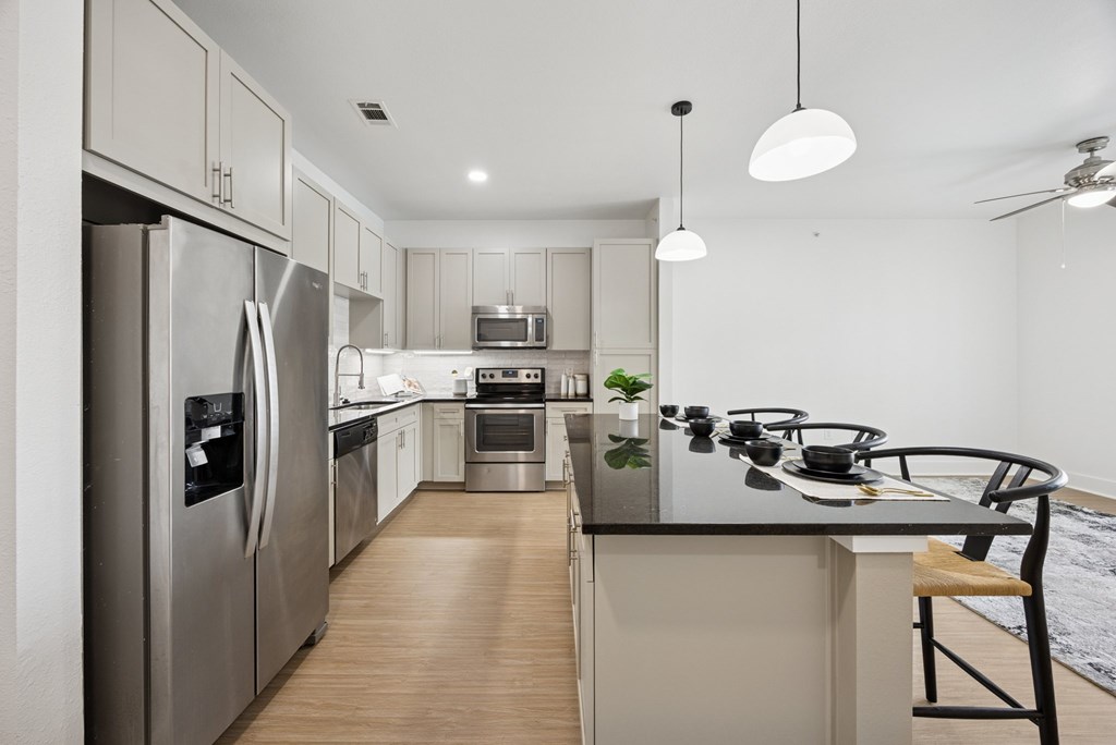 A modern kitchen with stainless steel appliances and wooden flooring.