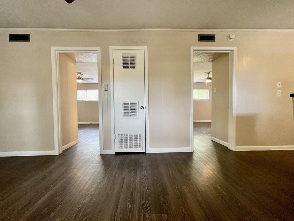 an empty living room with wood floors and an open door