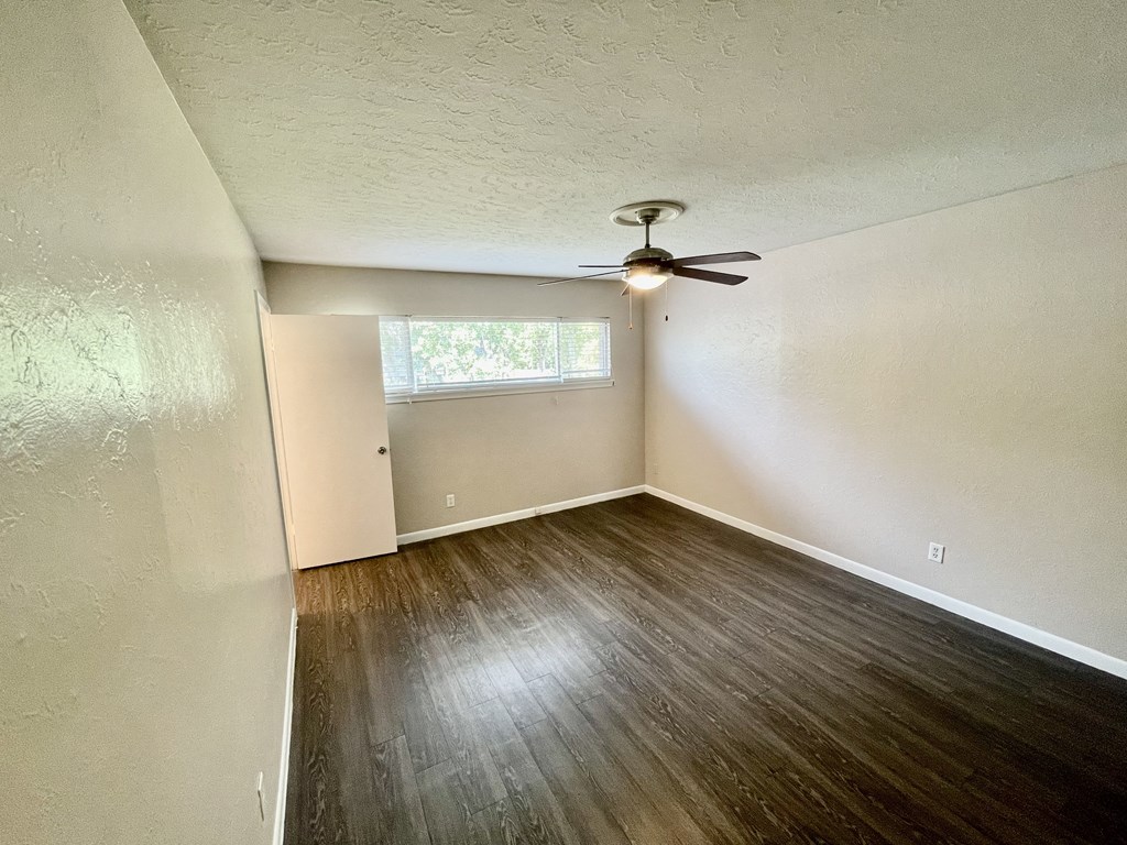 an empty bedroom with wood floors and a ceiling fan