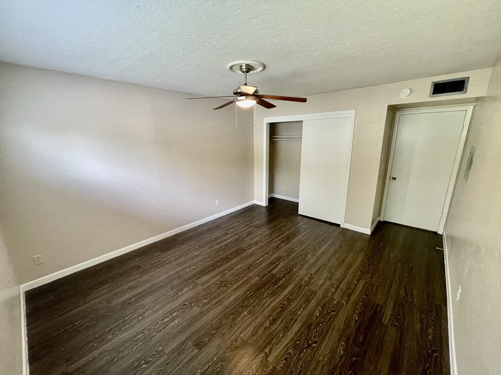 an empty living room with wood flooring and a ceiling fan