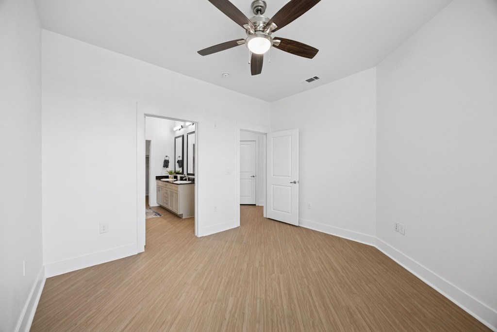 A room with a ceiling fan and wooden flooring.